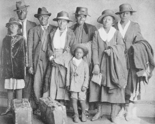 A family poses for a portrait while carrying person items and suitcases